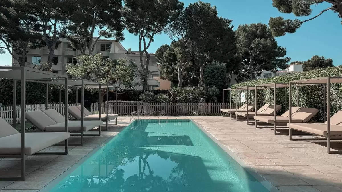 Piscina al aire libre en Mallorca con tumbonas beige, entorno natural y diseño simétrico para relajación