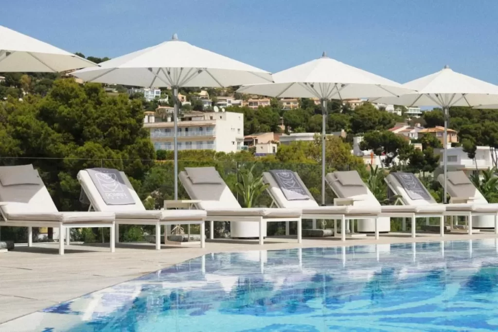 Piscina al aire libre en Mallorca con tumbonas, sombrillas blancas y entorno residencial tranquilo y soleado