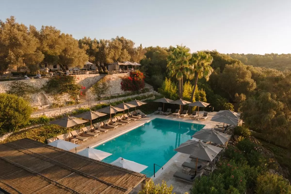 Finca Serena Mallorca, Small Luxury Hotels Piscina al aire libre en Mallorca con tumbonas, sombrillas neutras y entorno natural de vegetación y piedra