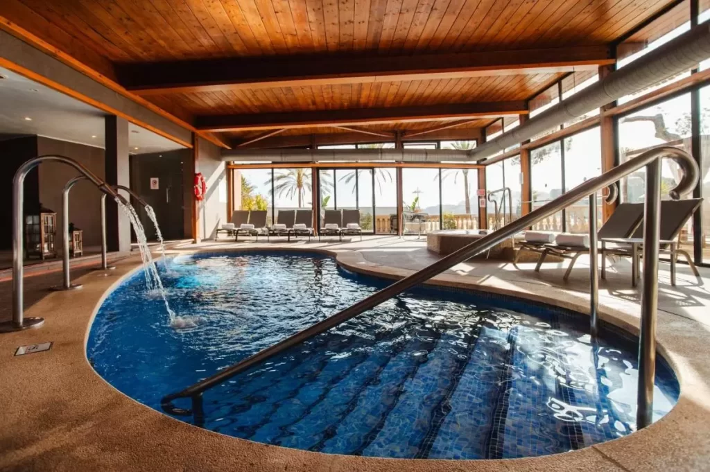 Piscina climatizada interior con jacuzzi, tumbonas y diseño moderno en Mallorca con vistas naturales