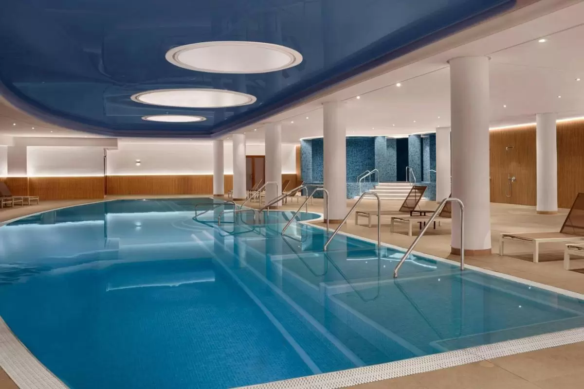 Piscina cubierta moderna con jacuzzi y área de descanso en espacio cerrado con iluminación suave en Mallorca