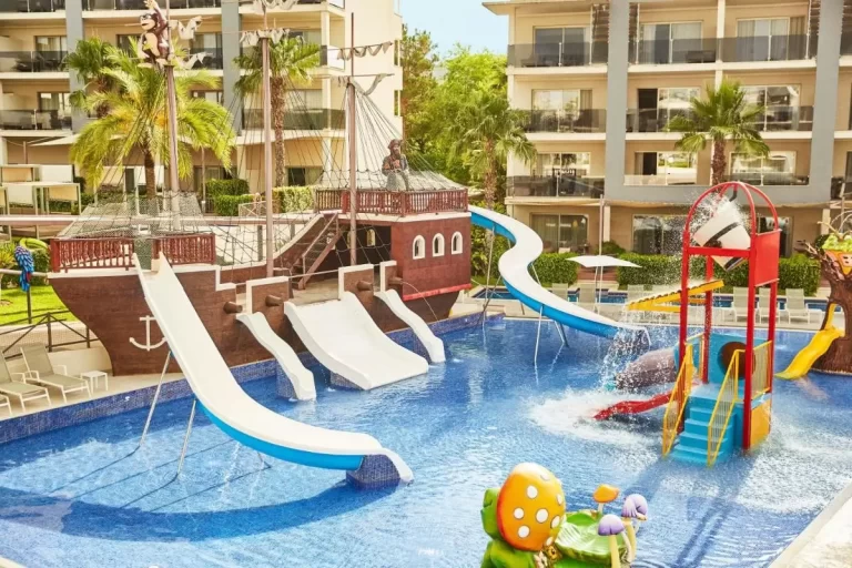 Piscina infantil con toboganes, juegos acuáticos y decoración temática en entorno exterior con palmeras en Mallorca