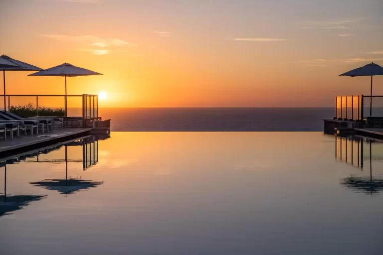 Piscina infinita con vistas al mar en Mallorca al atardecer con tumbonas y sombrillas para relajación