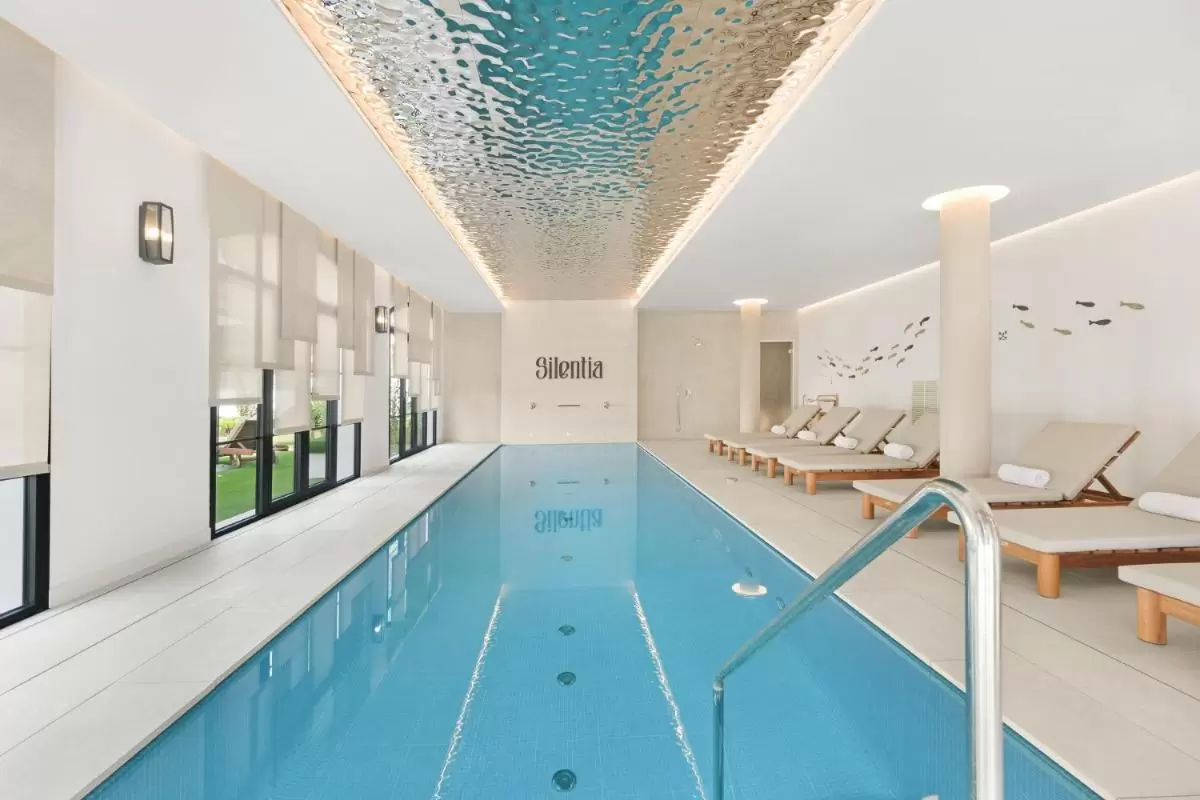 Piscina interior con diseño relajante, tumbonas de madera y decoración acuática en Mallorca