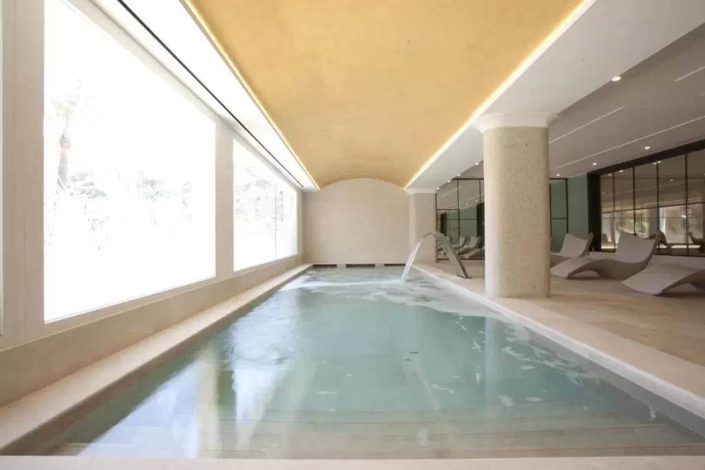 Piscina interior minimalista en Mallorca con diseño natural, iluminación cálida y estructura arqueada de agua
