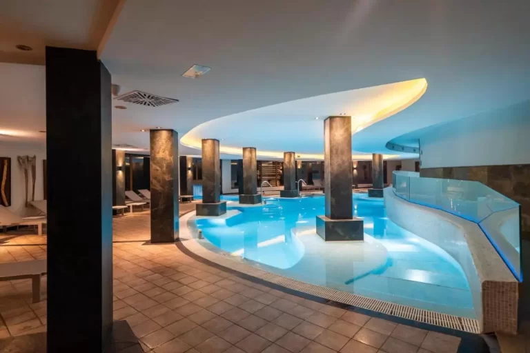 Piscina interior moderna con diseño irregular, iluminación azulada y ambiente relajante en Mallorca