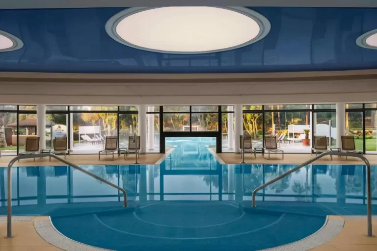 Piscina interior moderna y simétrica con jacuzzi circular y amplios ventanales en Mallorca