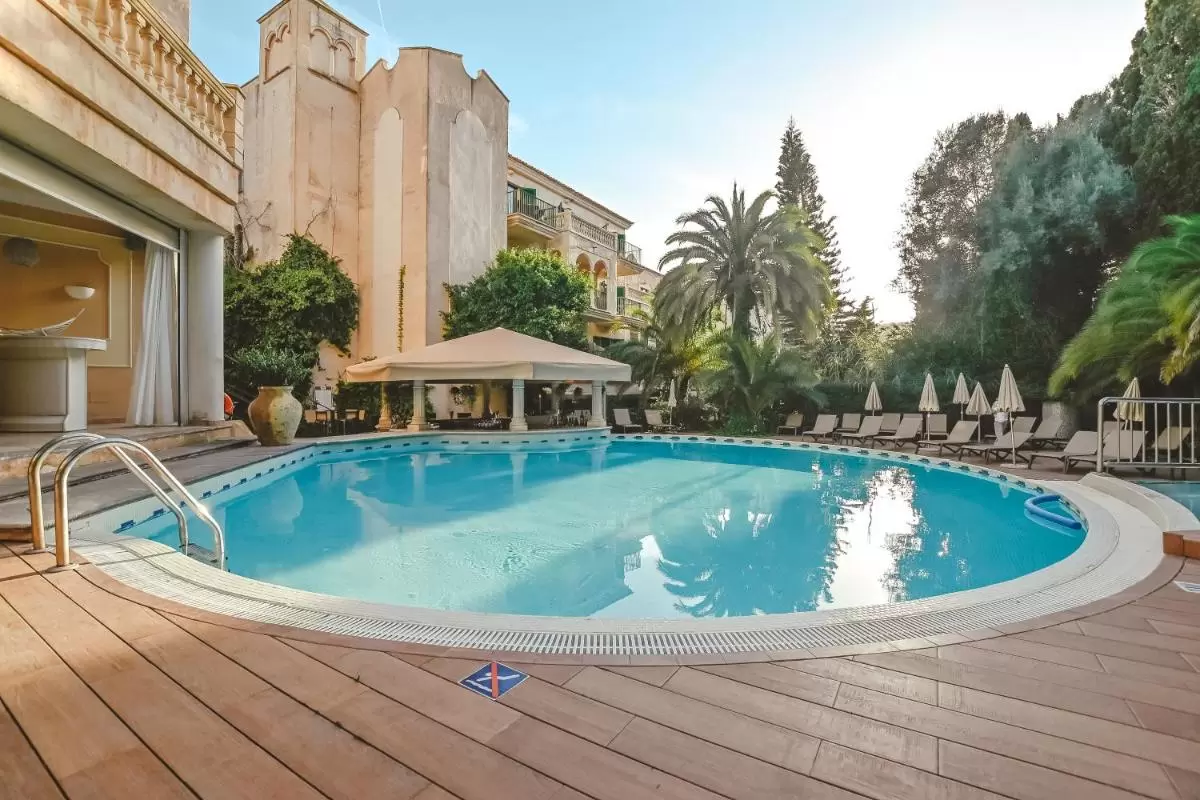 Piscina ovalada al aire libre con deck de madera y área de descanso en entorno natural en Mallorca