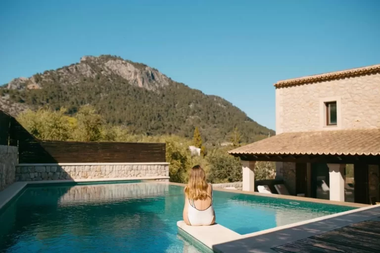 Piscina rectangular con agua clara y zona exterior de piedra en entorno natural soleado en Mallorca
