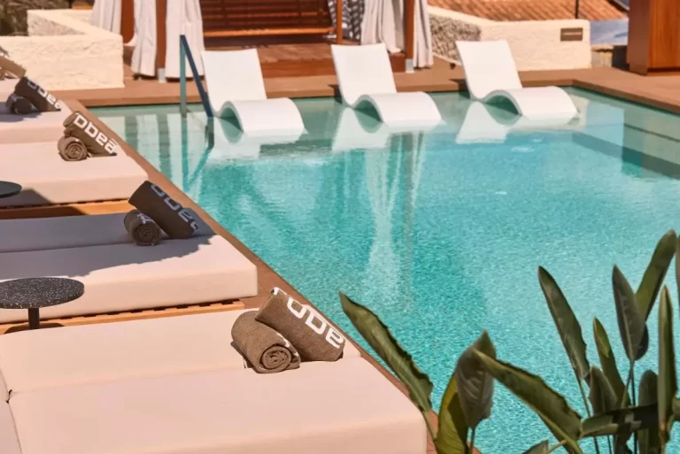 Piscina rectangular con agua turquesa, tumbonas beige y reposeras blancas sumergidas en Mallorca