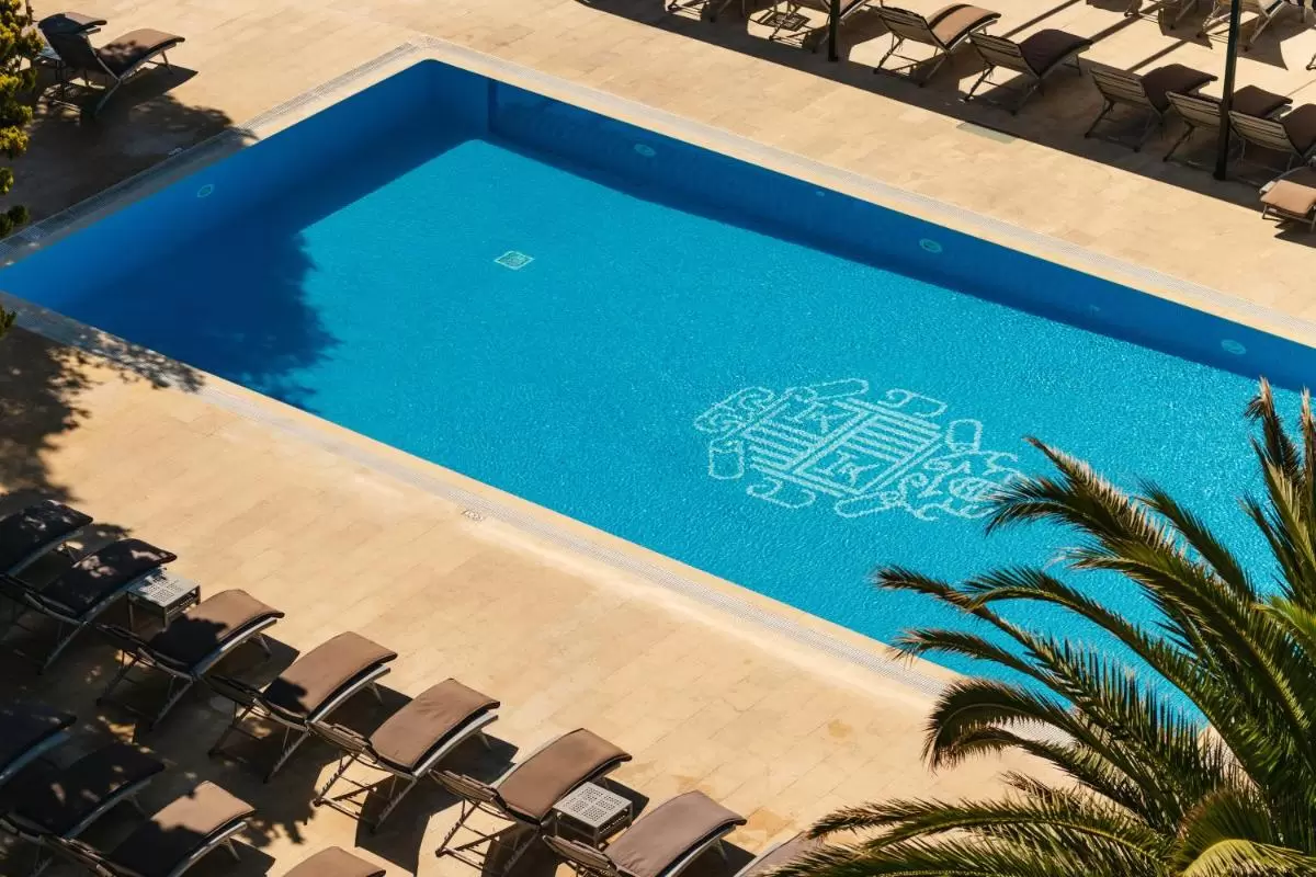 Piscina rectangular con diseño decorativo y área de descanso con tumbonas en Mallorca bajo luz natural