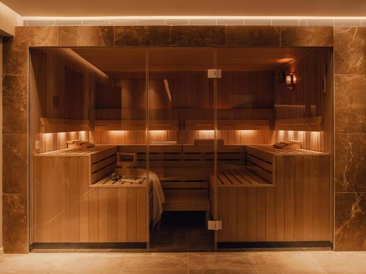 Aethos Hotel Mallorca Sauna de madera clara con iluminación cálida y puerta de vidrio templado en ambiente de spa en Mallorca