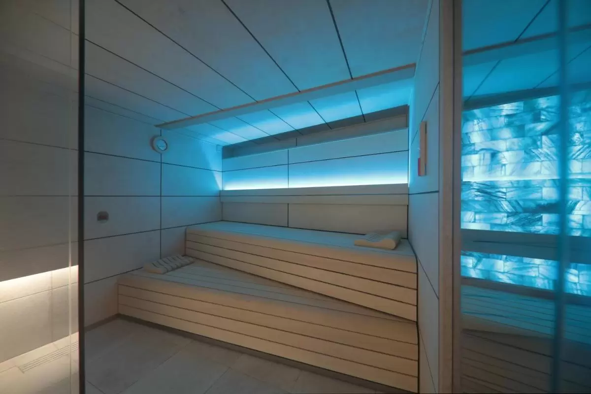 Sauna moderna minimalista en Mallorca con bancos de madera clara y luz ambiental azulada