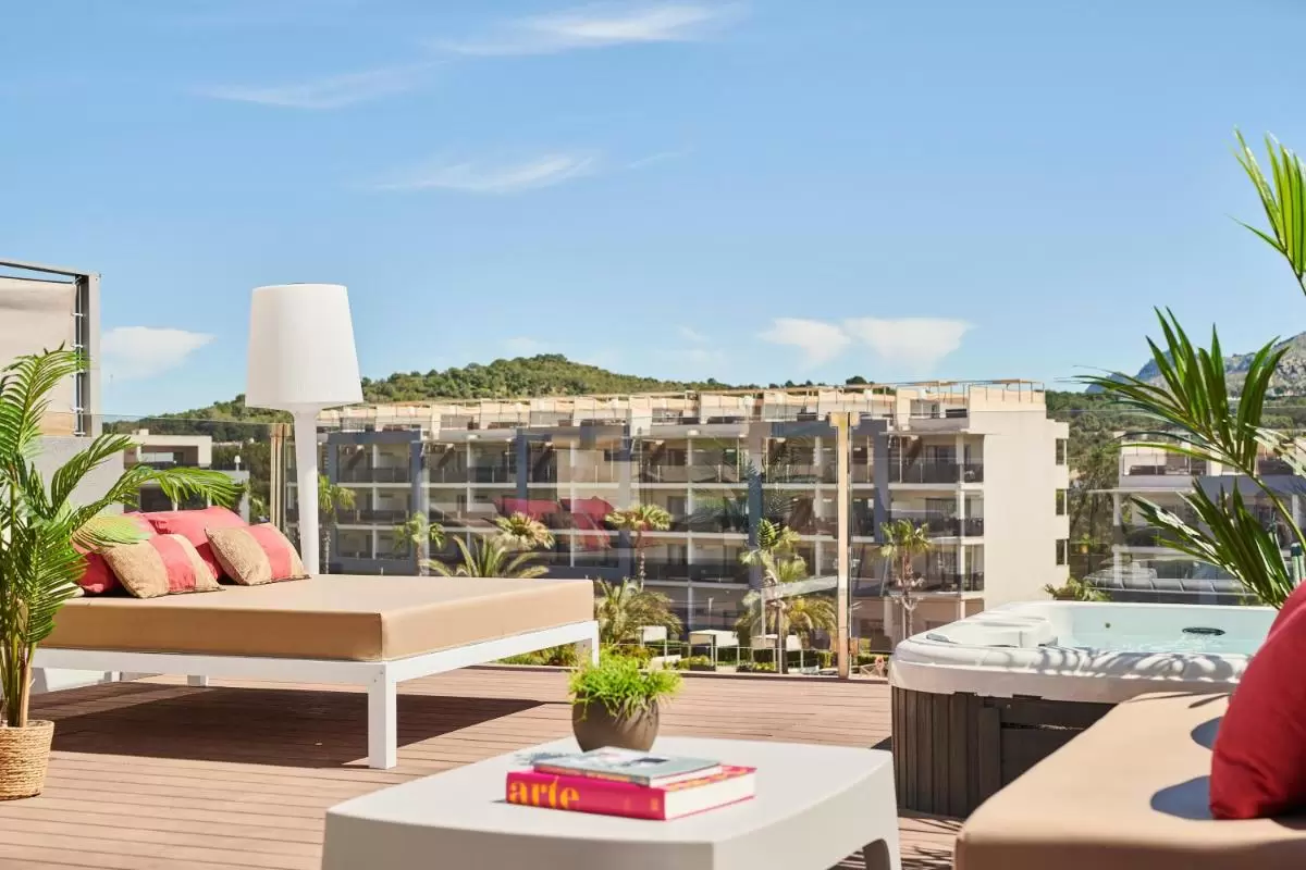 Terraza al aire libre en Mallorca con jacuzzi, sofá cama y vistas a colinas y edificio residencial