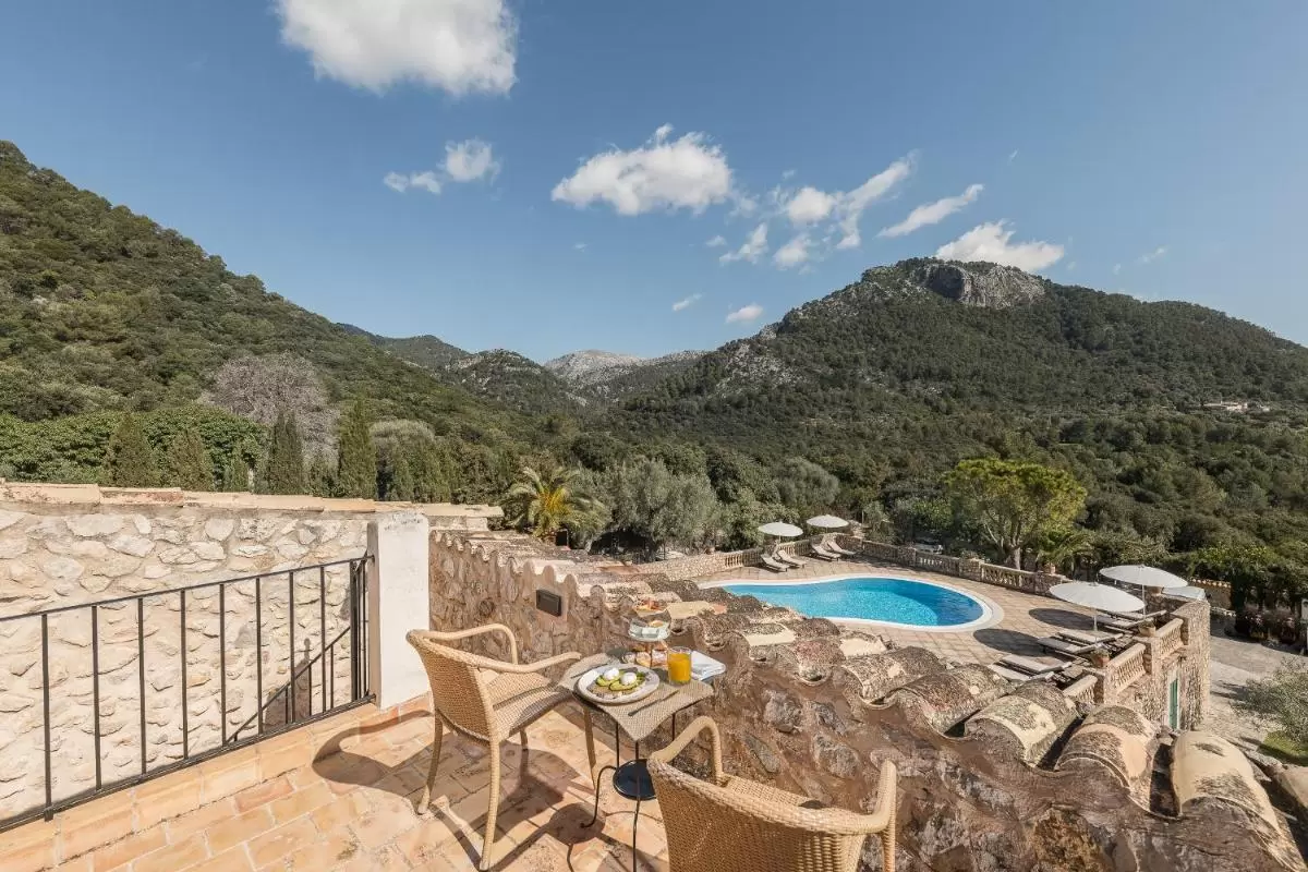 Terraza con mobiliario de mimbre y piscina irregular rodeada de naturaleza en Mallorca