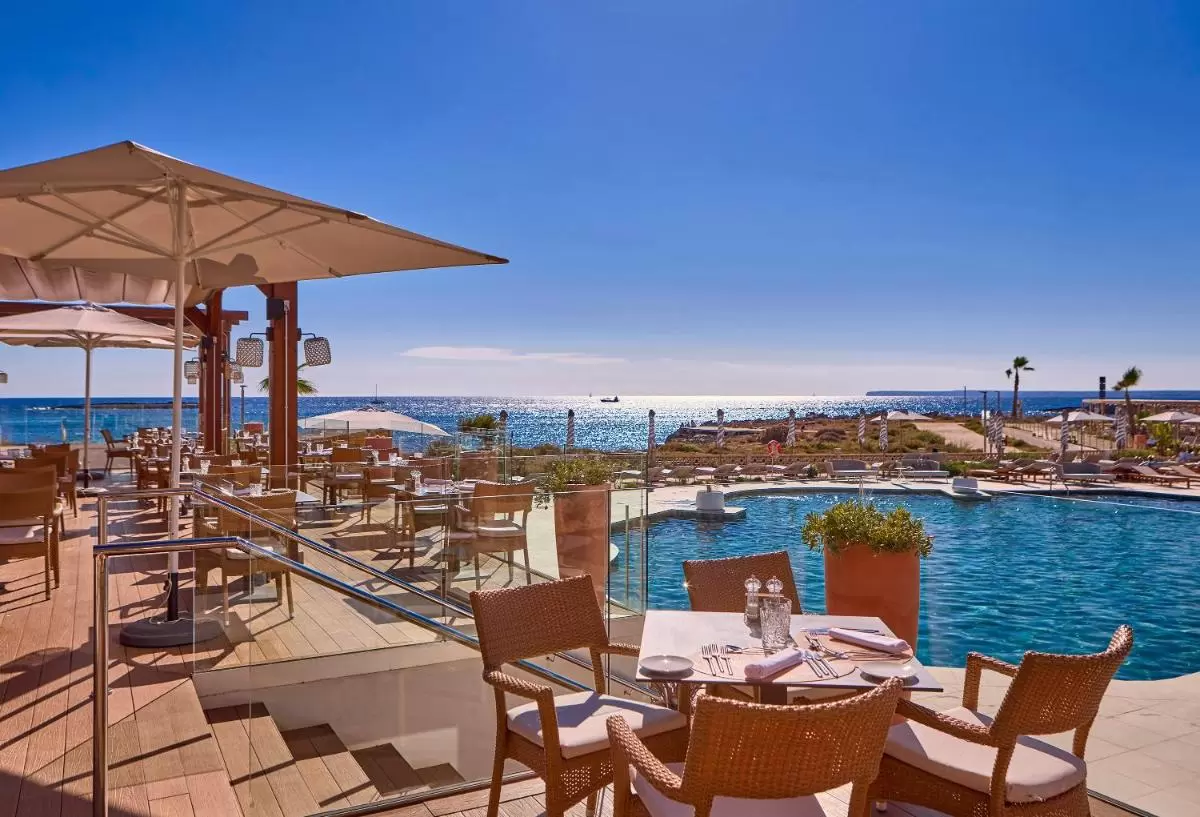 Terraza con piscina irregular, mobiliario de mimbre y vistas al mar en Mallorca al aire libre