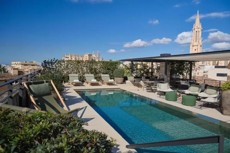 Terraza con piscina rectangular y zona de descanso con tumbonas y mobiliario bajo sombra en Mallorca
