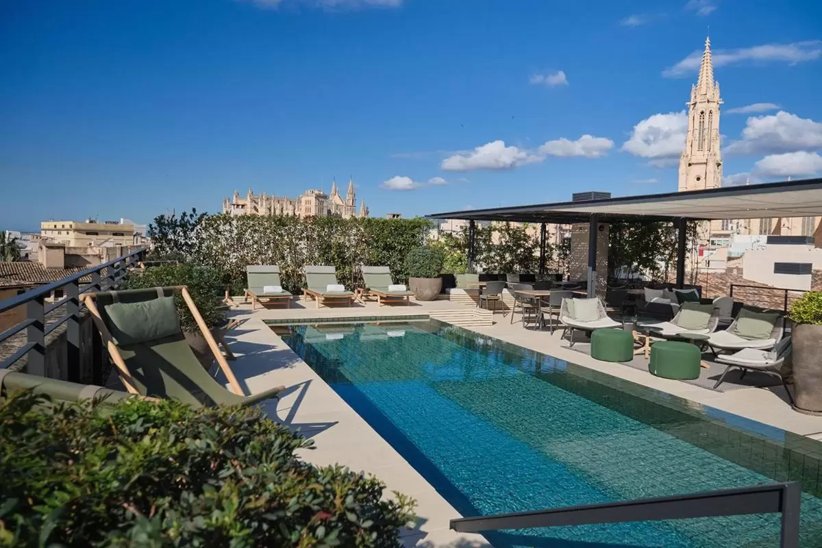 Terraza con piscina rectangular y zona de descanso con tumbonas y mobiliario bajo sombra en Mallorca