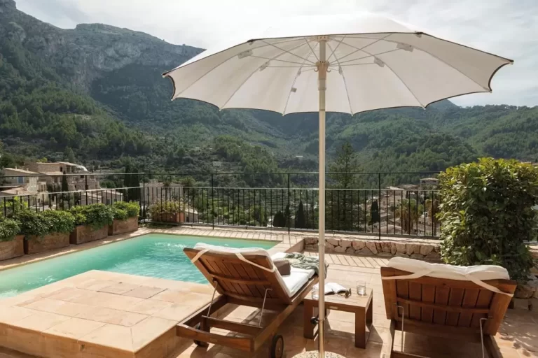 Terraza con piscina y tumbonas de madera en Mallorca con vistas a valle montañoso y vegetación natural