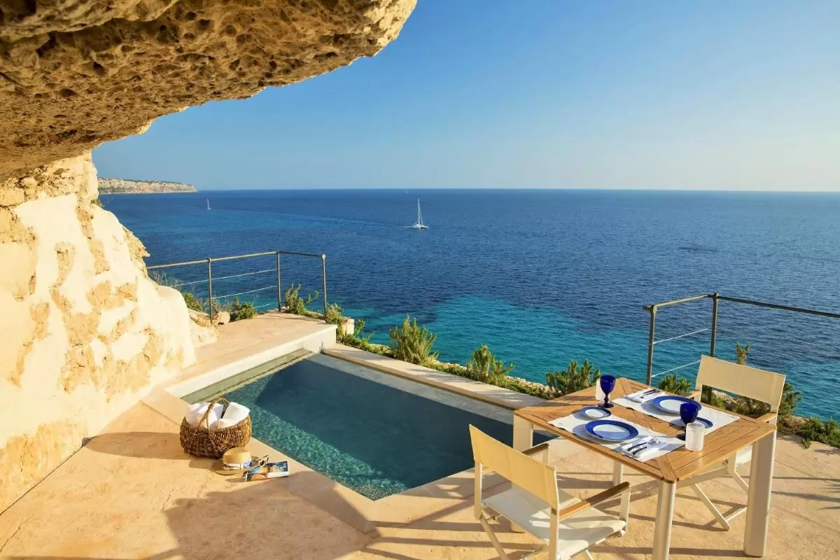 Terraza con piscina y vistas al mar en Mallorca con mobiliario exterior y barandilla metálica segura