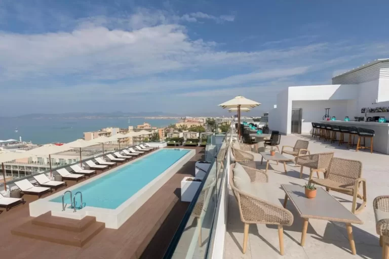 Terraza elevada con piscina rectangular, área de descanso y bar con vistas panorámicas al mar en Mallorca