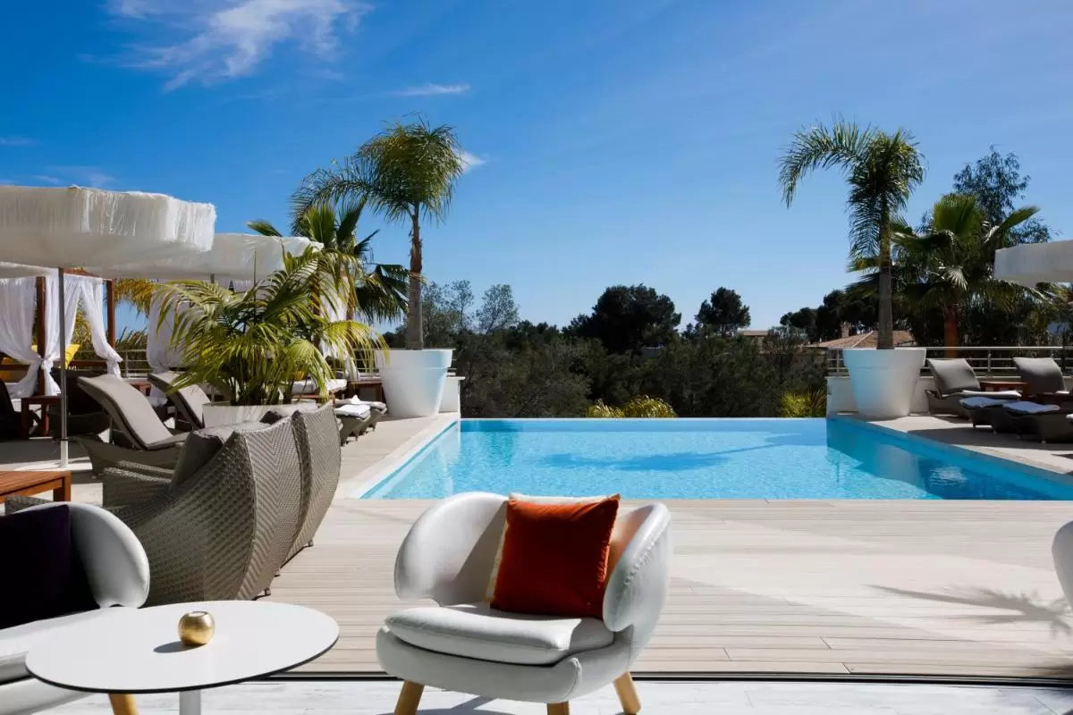 Terraza exterior con piscina de borde infinito y áreas de descanso modernas en Mallorca