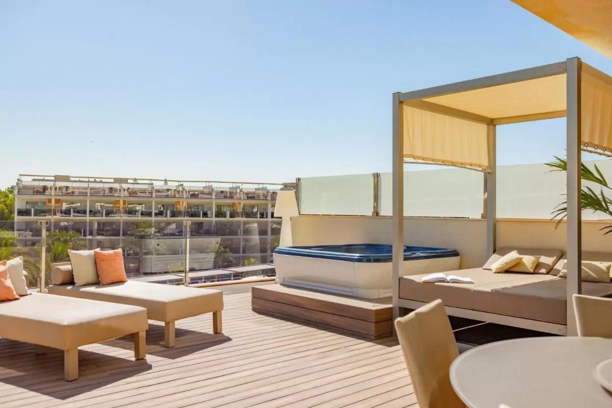 Terraza moderna en Mallorca con jacuzzi elevado, camastros acolchonados y área de descanso con toldo beige