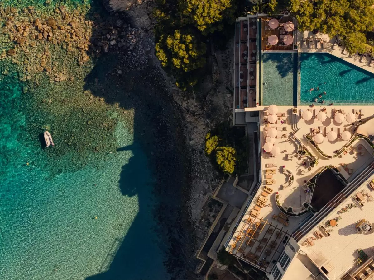 Vista aérea de complejo costero con piscina, terrazas y vegetación junto a costa rocosa en Mallorca