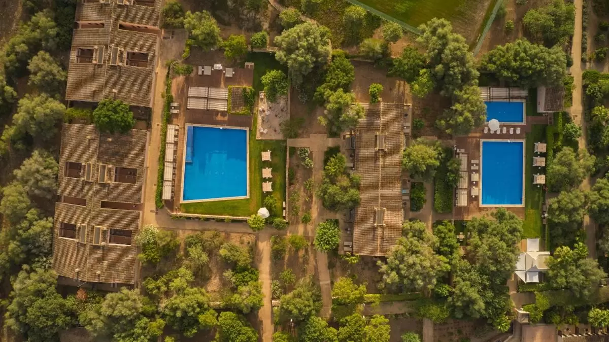 Vista aérea de complejo residencial en Mallorca con piscinas, áreas verdes y caminos pavimentados