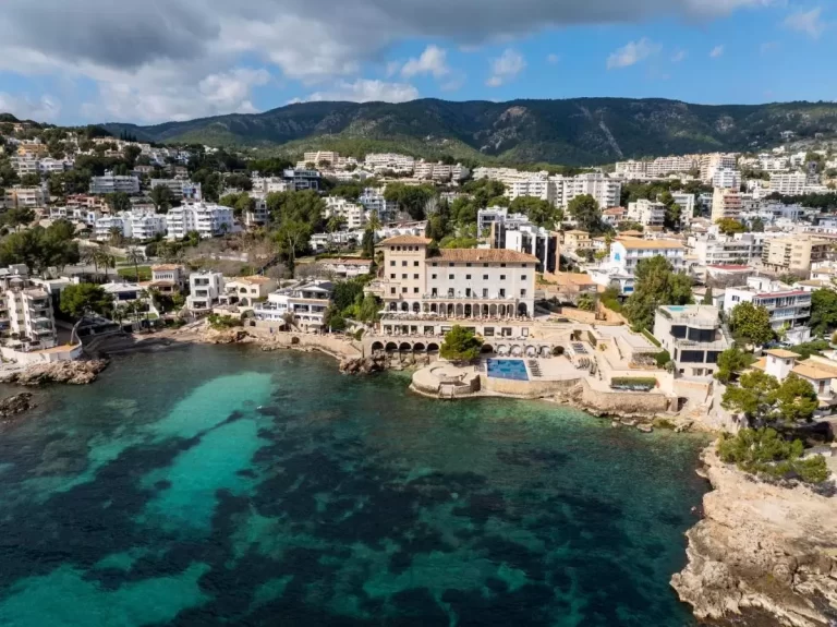 Vista aérea de zona costera en Mallorca con piscina, edificaciones residenciales y paisaje natural mediterráneo
