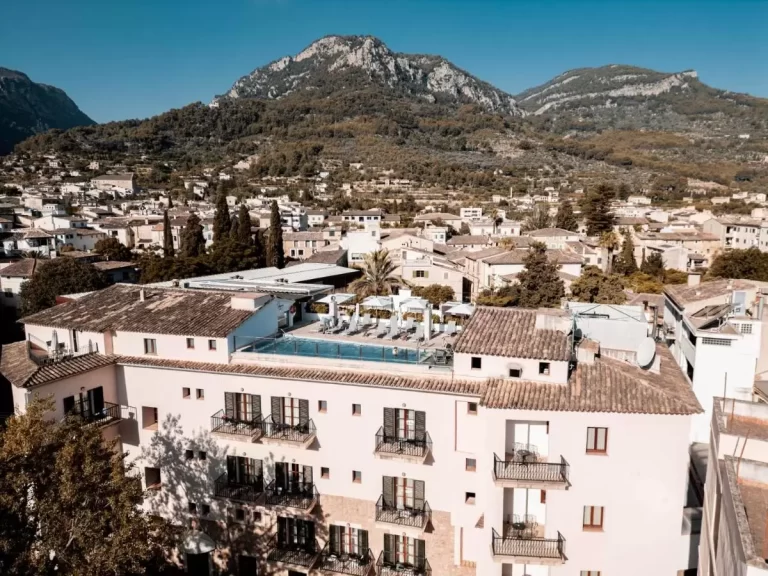 Vista panorámica de edificio residencial con piscina en azotea y paisaje montañoso en Mallorca