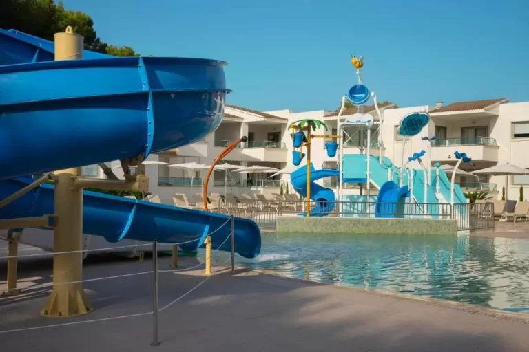 Zona de piscina al aire libre con juegos acuáticos y toboganes en Mallorca bajo cielo despejado