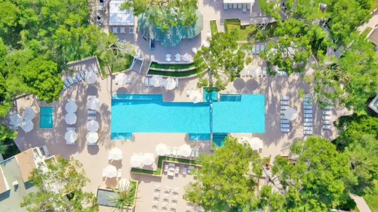Zona de piscina al aire libre con piscina rectangular y área de descanso circular en Mallorca rodeada de vegetación natural