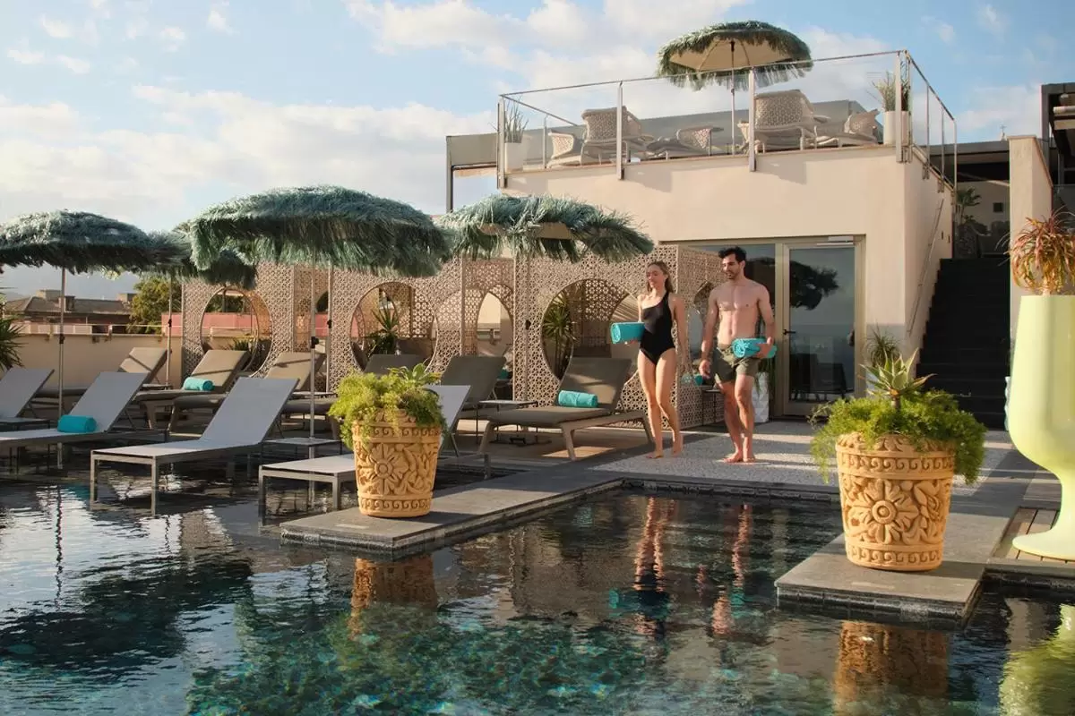 Zona de piscina al aire libre con tumbonas, sombrillas naturales y área de descanso en Mallorca